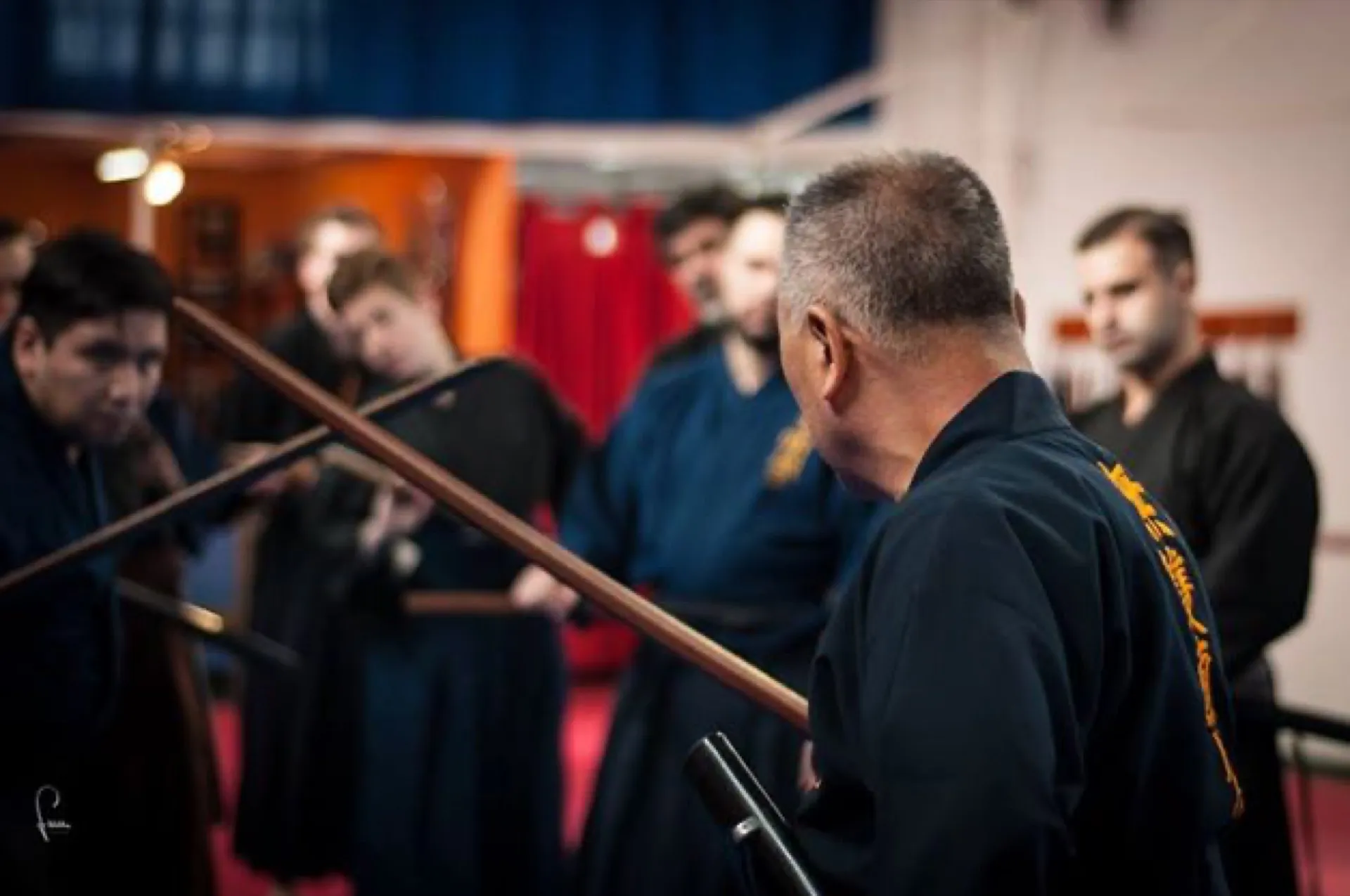 Sekiguchi sensei observando una práctica junto a alumnos, bokken cruzados en primer plano